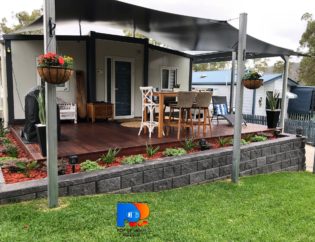 established tiny / small home with deck, block retaining wall and outdoor furniture and bbq