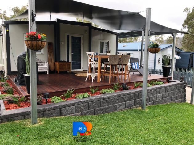 established tiny / small home with deck, block retaining wall and outdoor furniture and bbq