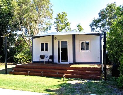 small / tiny home installed into backyard bathed in morning sunshine and cool shade