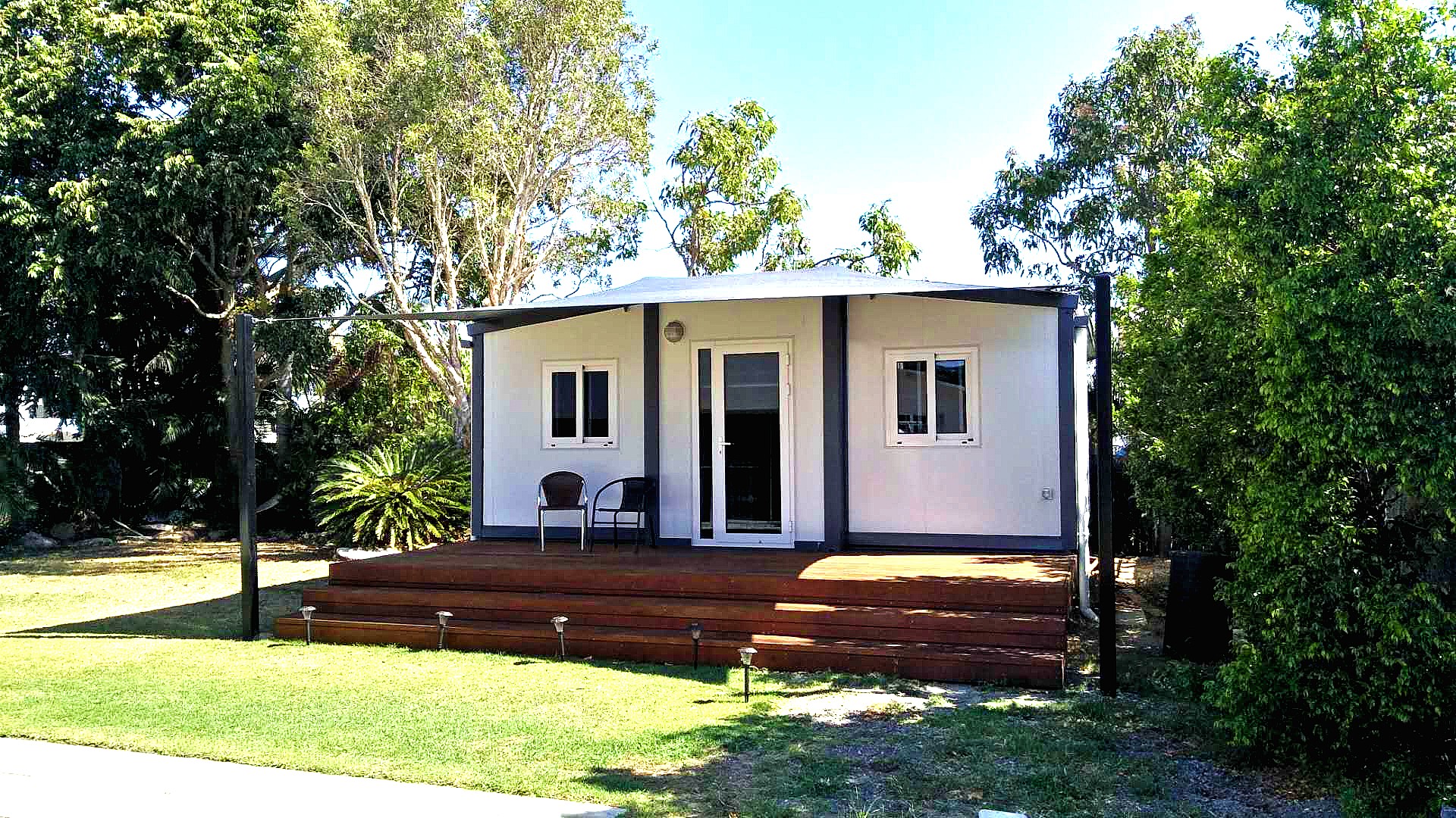 small / tiny home installed into backyard bathed in morning sunshine and cool shade