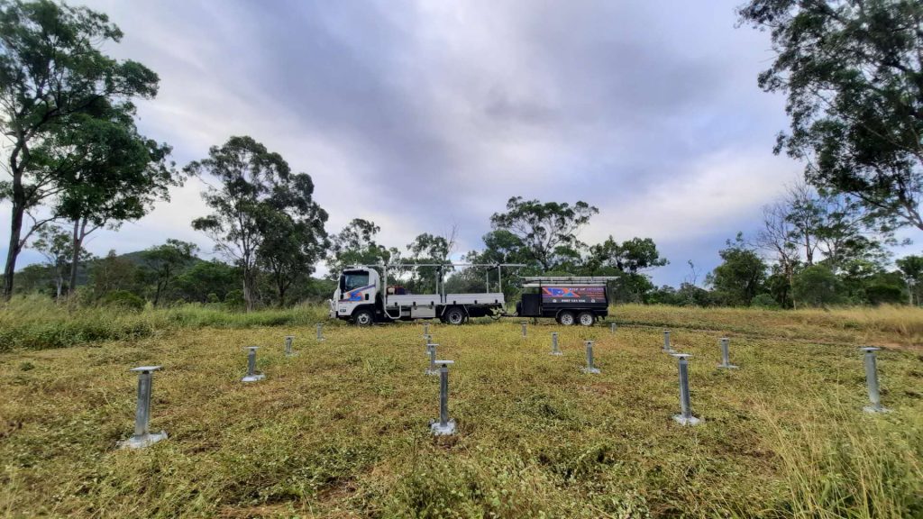 Pop Up Homes footings in paddock with work truck and trailer